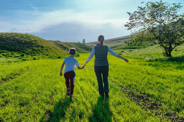 Mother and son walking in the field holding hands