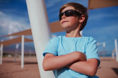 Kumsalda güneş gözlüklü yakışıklı bir çocuğun portresi.