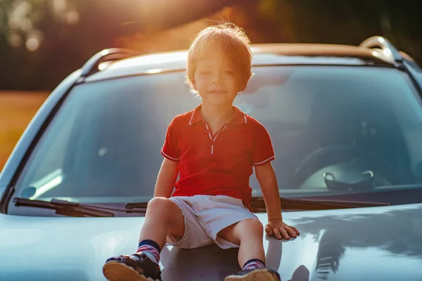 2歳の子供は車のフードに座っています — ストック写真