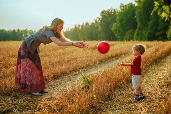 年轻的母亲和两岁的儿子在田里玩球 — 图库照片