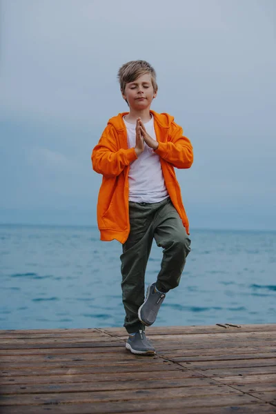海の端で瞑想ポーズに立つ男の子 — ストック写真