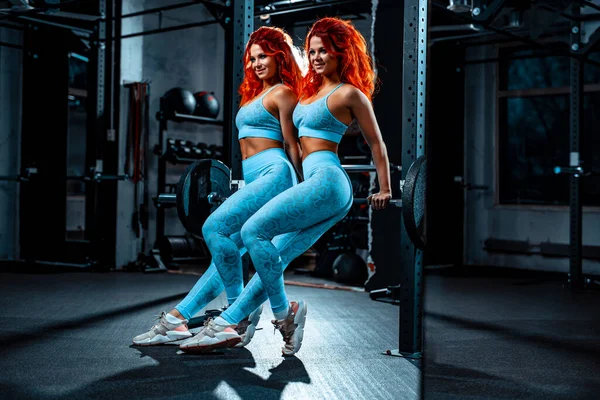 年轻的双胞胎女子运动队在体育馆摆姿势 — 图库照片
