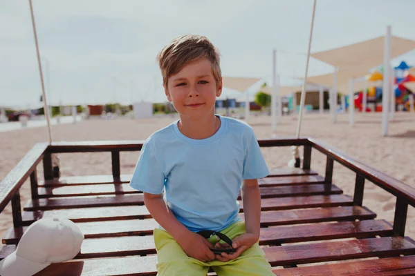 夏にビーチでスイングに座って男の子の肖像画 — ストック写真
