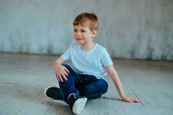 Bonito Menino Cinco Anos Idade Uma Camiseta Jeans Senta Chão — Fotografia de Stock