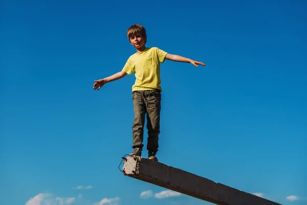 男孩在蓝天背景下走路和保持平衡 — 图库照片