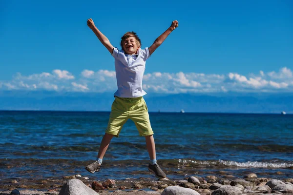 幸せな成功した少年は湖の海岸でジャンプ — ストック写真