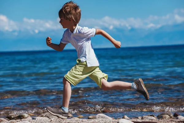 晴れた日に湖畔を走る少年 — ストック写真