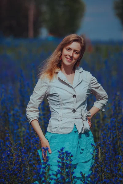 青い花の牧草地で美しいエレガントな女性の肖像画 — ストック写真