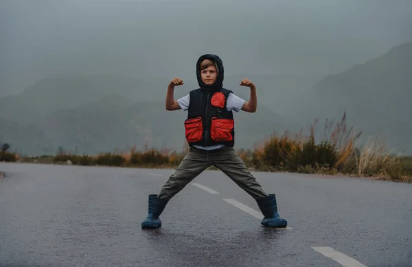 Chlapec Hrdinské Póze Stojí Asfaltové Cestě Deštivém Počasí — Stock fotografie