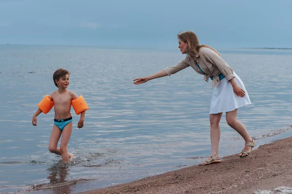 妈妈和淘气的孩子在海滨 妈妈叫孩子 他却跑掉了 — 图库照片