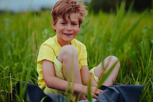 快乐的笑脸男孩坐在绿色的草地上 — 图库照片