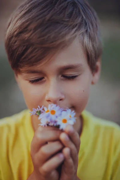 Vahşi Çiçeklerin Kokusunu Soluyan Yakışıklı Bir Çocuğun Portresi — Stok fotoğraf