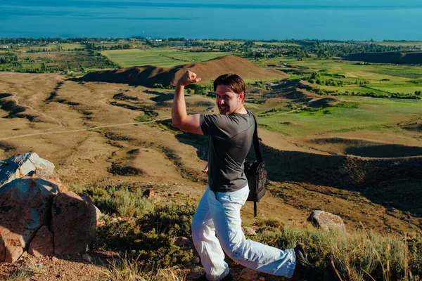 山の上に彼の強さを示す幸せな若い男の旅行者 — ストック写真