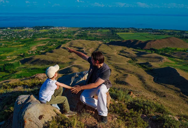 父亲和儿子坐在山顶上 望着远方 — 图库照片