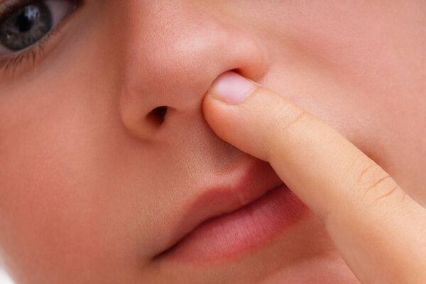 Baby picks his nose with his finger close-up view
