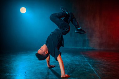 Boy breakdancing in dark studio with lights clipart