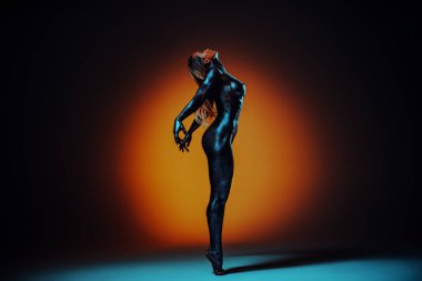 Siyah boyalı çıplak bir kadın. Vücudu koyu renk, kırmızı benekli.