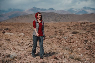 Genç gülümseyen kadın turist dağlarda yürüyor.