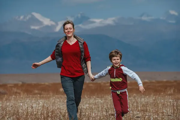 Happy mother and son running on mountains background at autumn