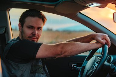 Gün batımında araba süren yakışıklı genç adam.