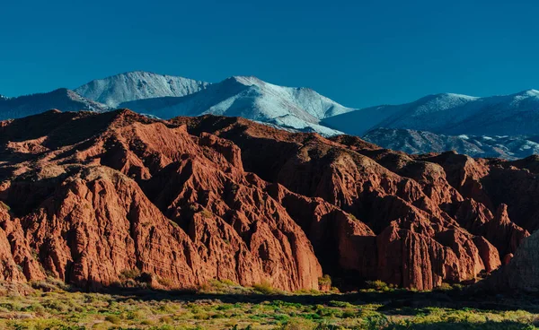 Picturesque landscape with red mountains and snowy peaks
