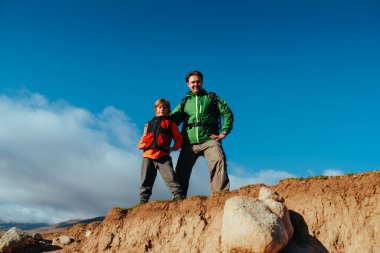 Baba ve oğul turistler dağın tepesinde duruyorlar.