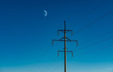 Mavi gökyüzü arka planında büyük uydulu elektrik hatları