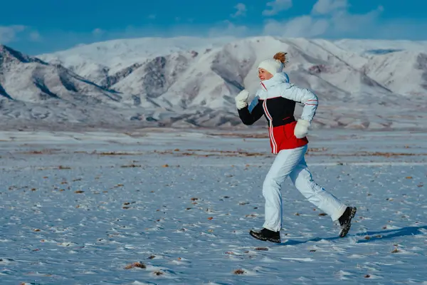 Sport woman tourist runs on mountains background in winter season