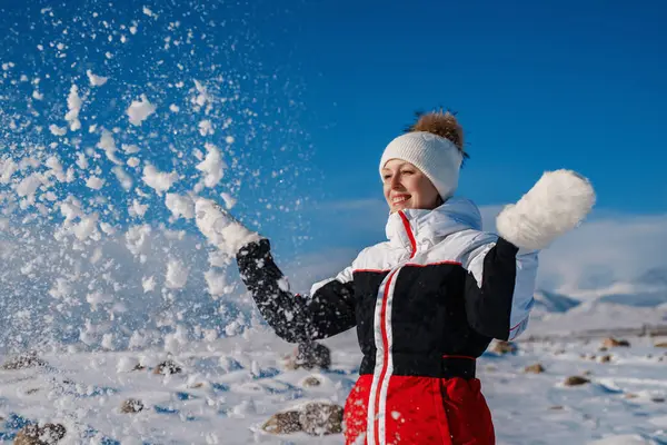 年轻快乐的女人在冬天的山上扔雪 — 图库照片