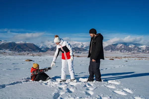 Ebeveynler Kışın Arka Plandaki Dağlarda Kar Yığınından Tırmanmasına Yardım Eder — Stok fotoğraf