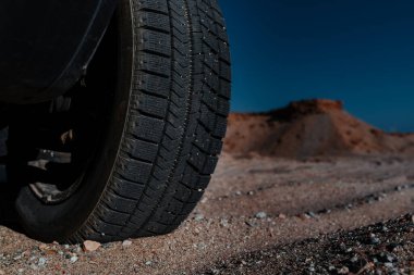 Otomobil tekeri kumun üzerinde, dağların yakın görüntüsünde.