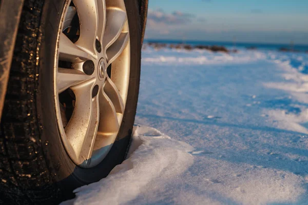 Car wheel in snow in winter season at sunset