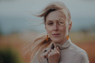 Rüzgarda dalgalanan saçları olan güzel genç bir kadının romantik portresi.