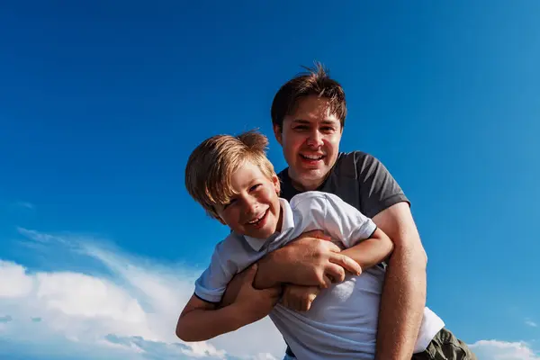 天空の背景で楽しんでいる幸せな父親と息子 — ストック写真