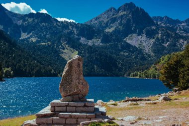 Pyrenees Dağları 'ndaki pitoresk göl kıyısında bir heykel üzerinde taş.