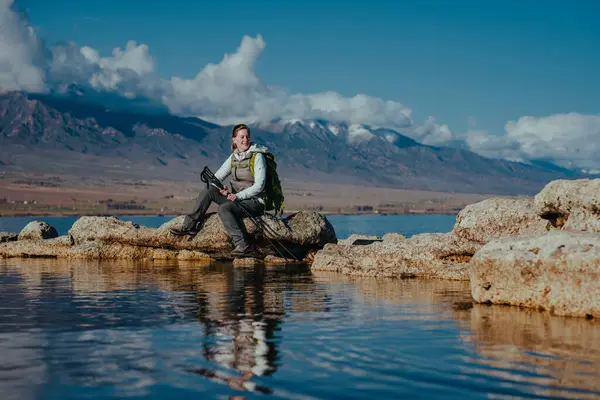 Turis Wanita Duduk Atas Batu Danau Dengan Latar Belakang Pegunungan Stok Foto