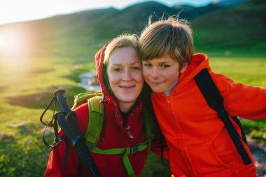 Mutlu anne ve oğul portresi. Gün batımında güzel bir dağ vadisinde turistler.