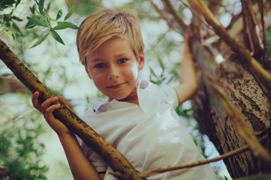 Ağaçta oturan güzel çocuğun portresi.
