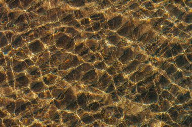 Deniz suyunun yüzeyinde güneş parlıyor.