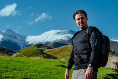 Sırt çantalı adam dağların arkasındaki vadide duruyor.