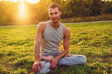 Yogi adam portresi yaz günü parkta, sıcak günbatımı ışığı