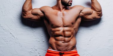 Beyaz arka planda güçlü bir vücut geliştiren genç adam.