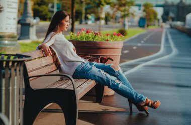 Yaz kenti caddesinde bankta oturan genç ve güzel bir kadın