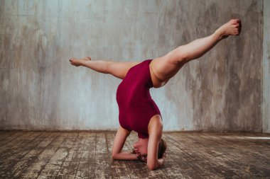 Stüdyoda baş aşağı uzanan genç, güzel bir Yogi kadın.