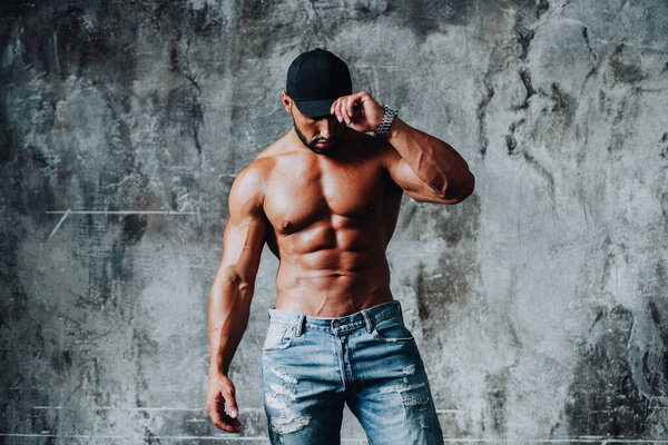 Молодой сильный человек культурист в джинсах на фоне каменной стены