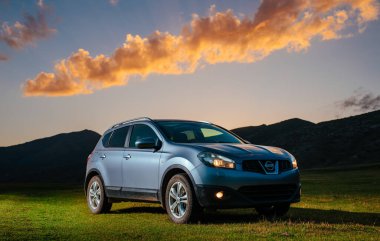 Kırgızistan - 19 Ağustos 2023 Nissan Kashqai arabası yaz günbatımında dağlarda duruyor