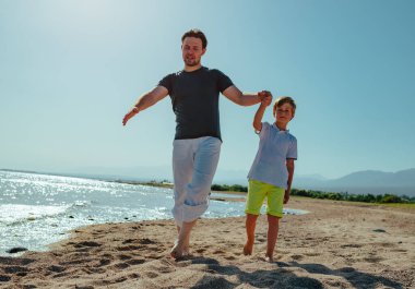 Baba ve oğul yaz günü göl kıyısında yürüyorlar.