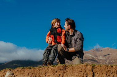 Baba ve oğul turistler dağlarda poz veriyorlar.