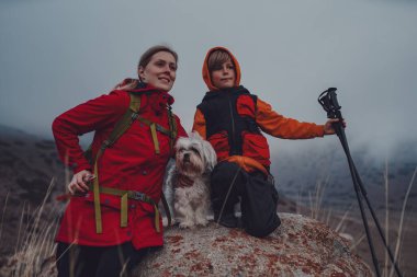 Anne ve oğlu Shih Tzu köpek portresiyle dağlarda dramatik havalarda.