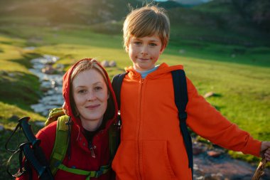 Gün batımında dağ vadisinde oğluyla birlikte genç bir turist.